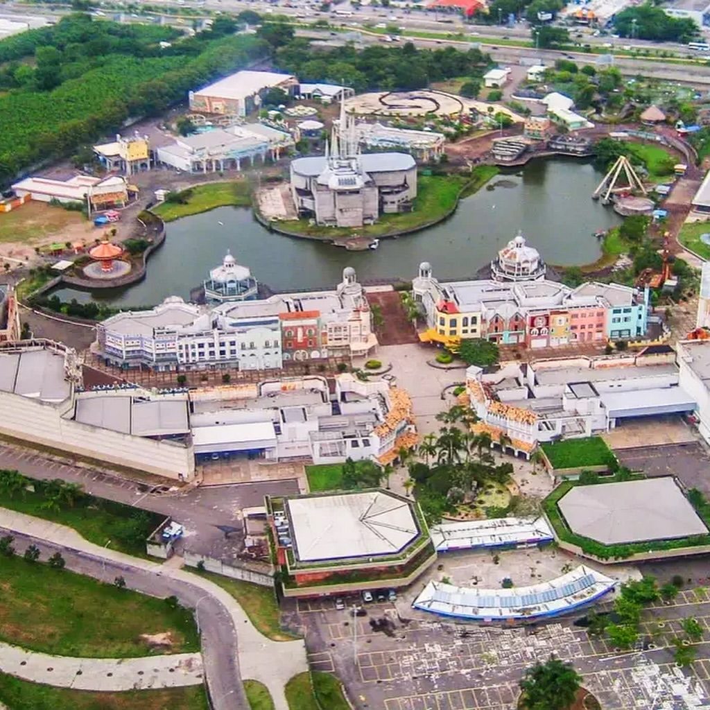 Foto aérea real do antigo parque Terra Encantada antes da demolição, com lago e atrações