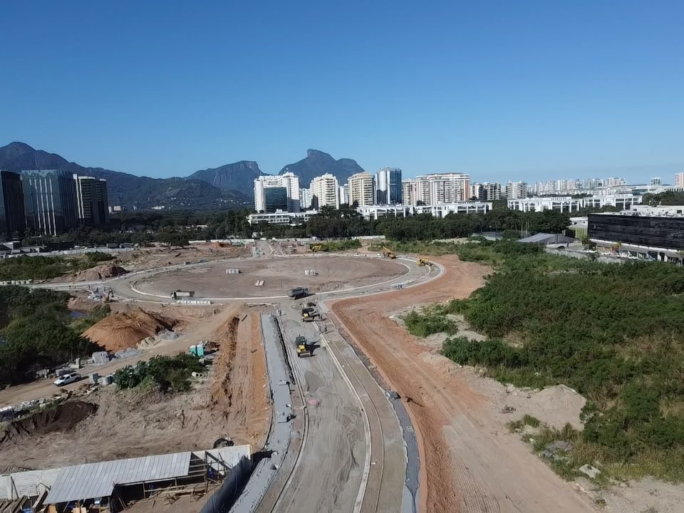 Foto aérea real da via de acesso que leva à rotatória do Park Avenue, com a Pedra da Gávea ao fundo